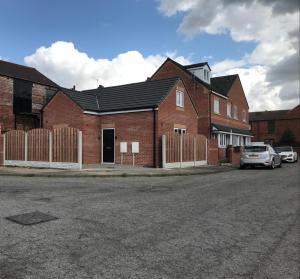 a red brick house with a fence in front of it at Lovely Modern 3 Bedroom House Doncaster, Family Contractor Friendly, Sleeps 6 in Carcroft