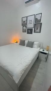 a white bed in a room with pictures on the wall at Saphir Townhouse 5 to 6 pax rooftop terrace, Cavite in Imus