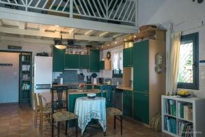 una cocina con armarios verdes y una mesa con sillas en Nerotrivia Villa - Ocean Panorama and Lush Gardens en Nerotriviá