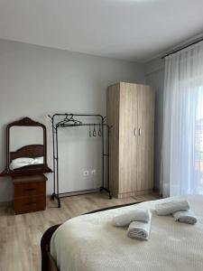 ein Schlafzimmer mit einem Bett, einem Spiegel und einer Kommode in der Unterkunft Inizio Apartment in Shkodra