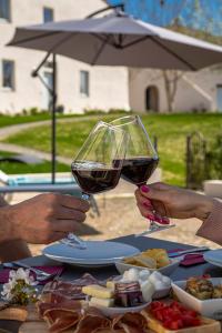 dos personas sosteniendo copas de vino en una mesa con comida en Relais Borgo Elissa en Certaldo