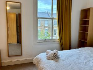 a bedroom with a bed and a mirror and a window at Stay in Islington in London