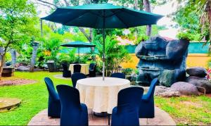 einen Tisch mit Stühlen und einen Sonnenschirm in einem Garten in der Unterkunft Sima's Cottage in Anuradhapura