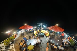 um grupo de pessoas sentadas a mesas num convés à noite em Halong Dragon Bay Cruise em Ha Long