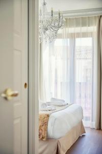 a bedroom with a bed with a chandelier and a window at Casa Palacio Reina de Tardajos in Vinuesa