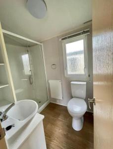 ein Bad mit einem WC, einem Waschbecken und einem Fenster in der Unterkunft The salsa golden gate towyn in Kinmel Bay