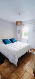 een groot wit bed met blauwe kussens in een kamer bij La maison du bonheur in Saint-Jean-de-la-Rivière