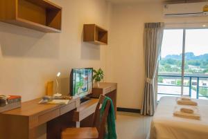 a room with a bed and a desk with a television at Krabi Cinta House in Krabi town