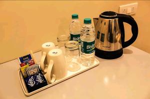 Hotel HRS - New Delhi Railway Station في نيودلهي: كاونتر مع وعاء القهوة وزجاجات المياه