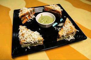 a black plate with some food on a table at Hotel HRS - New Delhi Railway Station in New Delhi +24 photos