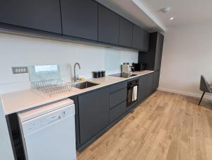 Il comprend une cuisine avec des armoires noires et du parquet. dans l'établissement Lovely 1 Bed Apartment - Old Trafford, à Manchester