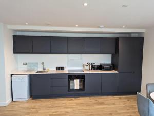 uma cozinha com armários pretos e electrodomésticos brancos em Lovely 1 Bed Apartment - Old Trafford em Manchester
