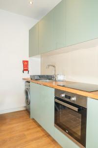 a kitchen with white cabinets and a sink and a dishwasher at Blue Nile Apartment - Liverpool in Liverpool