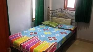 a bed with a colorful comforter and pillows on it at SPOT ON 93880 Guest House Bu Iin Syariah in Sidoarjo