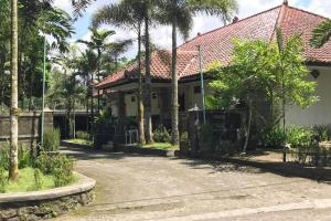 a house with palm trees and a driveway at Capital O 93882 The Pondok Palma Villa & Resto in Yogyakarta