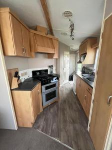uma cozinha com armários de madeira e um forno com placa de fogão em Two bedroom Caravan with Sea Views, Warden Springs Eastchurch em Warden