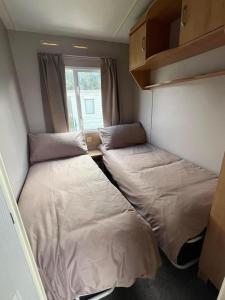 Duas camas num pequeno quarto com uma janela em Two bedroom Caravan with Sea Views, Warden Springs Eastchurch em Warden