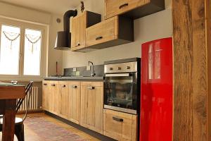 - une cuisine avec des placards en bois et un réfrigérateur rouge dans l'établissement Lo barbaboc, à Aoste