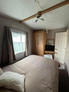 a bedroom with a large bed and a window at Two bedroom Caravan with Sea Views, Warden Springs Eastchurch in Warden