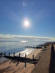 a beach with a fence and the sun in the sky at Two bedroom Caravan with Sea Views, Warden Springs Eastchurch in Warden