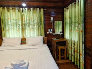 a bedroom with a bed with curtains and a mirror at Yungthong Baan Suan Resort in Ban Ko