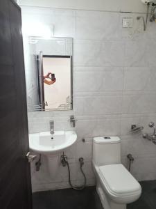 a person taking a picture of a bathroom with a toilet and sink at Hotel Best Velly in Gandhinagar