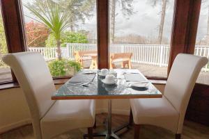 einen Esstisch mit 2 Stühlen und einen Tisch mit Tassen und Untertassen in der Unterkunft Killarney View House B&B in Killarney