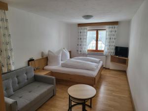 um pequeno quarto com uma cama e um sofá em Zum Eichhof em Reit im Winkl