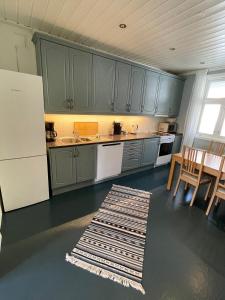 a kitchen with green cabinets and a table and chairs at Sentral og fargerik bygårdsleilighet in Halden