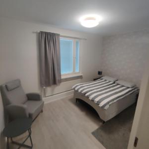 um quarto com uma cama, uma cadeira e uma janela em SEA - 3 Bedrooms em Kristiinankaupunki