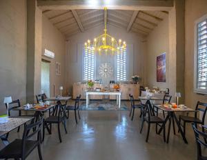 Habitación grande con mesas, sillas y lámpara de araña. en Relais Borgo Elissa en Certaldo