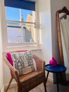une chaise avec un oreiller, une table et une fenêtre dans l'établissement Sandy Feet, St Eia Street. Cosy Cottage + Parking, à St Ives