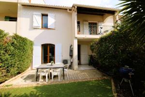a table and chairs in front of a house at CARBAU Maisonnette pour 8 personnes dans une résidence privée avec piscine à Carqueiranne in Carqueiranne