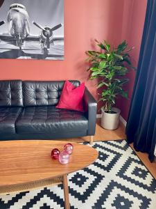 a living room with a black leather couch and a table at Sentral og fargerik bygårdsleilighet in Halden
