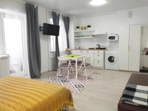 a white kitchen with a table and a dining room at Милая Студия 2 in Atyrau