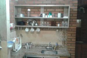 uma cozinha com um lavatório e uma prateleira com copos em Recanto beira rio - Sao Pedro da serra. em Nova Friburgo