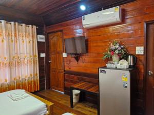 Habitación pequeña con nevera y TV. en Yungthong Baan Suan Resort en Ban Ko