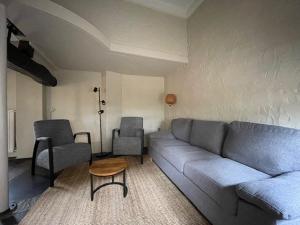 un soggiorno con divano e 2 sedie di Vakantiewoningen 'Hoeve de Witte Olifant' a Noorbeek