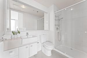 a white bathroom with a toilet sink and a shower at Skyline City Zen in Melbourne
