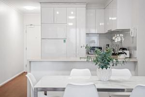 een keuken met witte kasten en een tafel en stoelen bij Skyline City Zen in Melbourne
