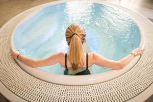 a woman sitting in a pool in a circular swimming pool at Kyriad Prestige Residence & Spa Cabourg-Dives-sur-Mer in Dives-sur-Mer