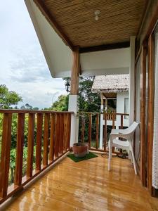 a wooden deck with a white chair on it at MHARI Bungalows & Studio Rooms in Tubod