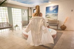 a woman in a white robe sitting in a room at Kyriad Prestige Residence & Spa Cabourg-Dives-sur-Mer in Dives-sur-Mer