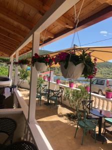 eine Terrasse mit Tischen, Stühlen und Topfpflanzen in der Unterkunft Villa Sarti in Ksamil