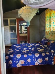 a bedroom with a bed with a blue comforter with flowers at Bungalow Chez Mouch Nosy Be 6 in Nosy Be