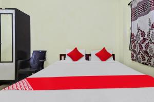 Un dormitorio con una cama con almohadas rojas y una silla en OYO Ruby Grand Inn Nallagandla, en Lingampalli