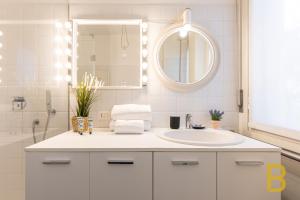 La salle de bains blanche est pourvue d'un lavabo et d'un miroir. dans l'établissement BePlace Apartments in Fiera, à Milan