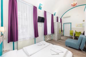 Habitación con 2 camas, silla y cortinas moradas. en Amber Gardenview Studios Downtown, en Budapest 31 fotos más
