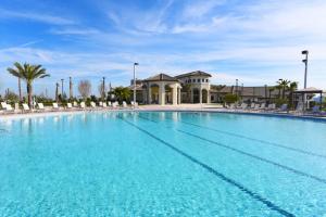 a large blue swimming pool with chairs and palm trees at 1581 PD - Exquisite 6BR Haven: Private Pool in Davenport