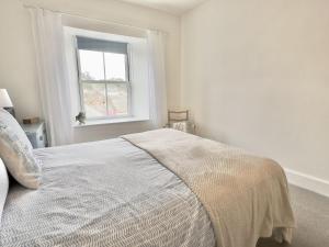 a white bedroom with a bed and a window at 10 Mill Road in Padstow
